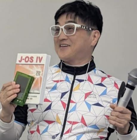 登壇する赤田進。J-OS IVを手にしたカラフルなジャージ姿。